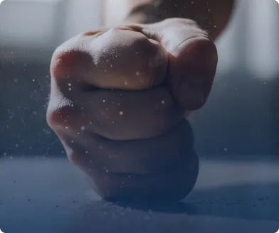 A clenched fist thrust toward the camera in dim light