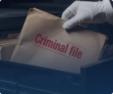 A gloved hand lifting a brown folder stamped Criminal file out of a records bin