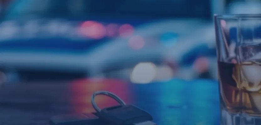 Car keys and a drink on a bar top under night traffic lights