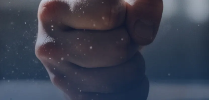 A clenched fist behind a rain-streaked window