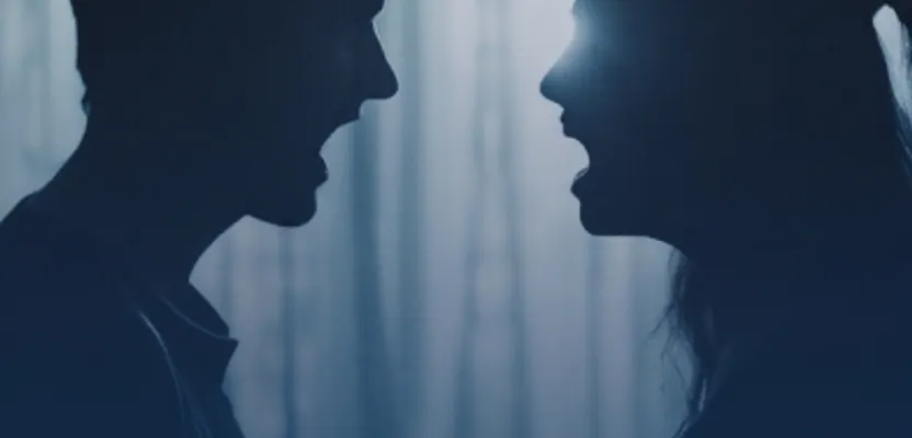 Two silhouettes facing each other in a darkened room
